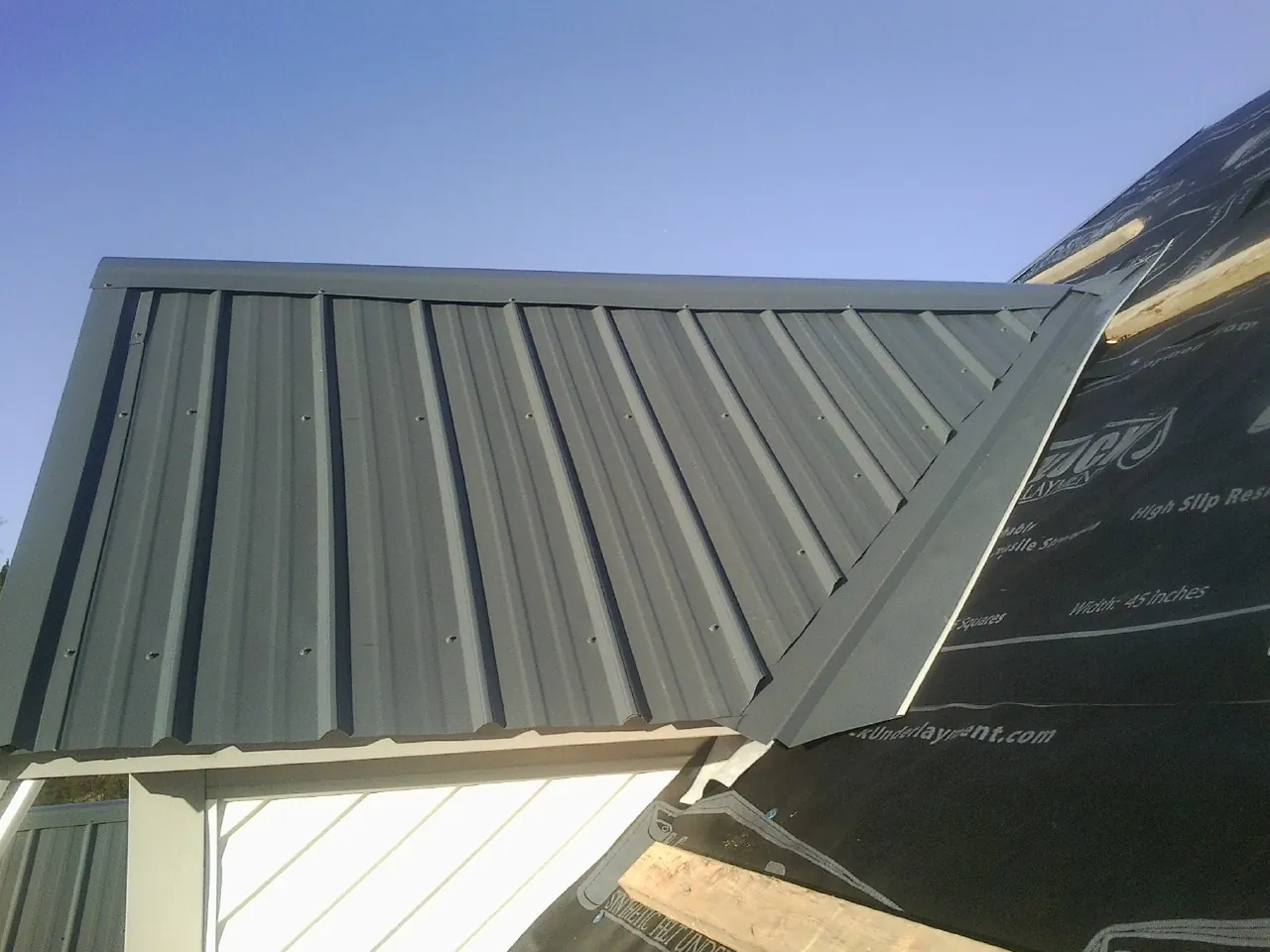 Gray metal roof panels going on over a garage gable in Frisco
