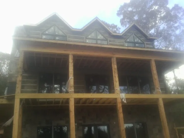 Dormers and porch framing on a large log home under construction — Roof Coating work by our crew in Frisco