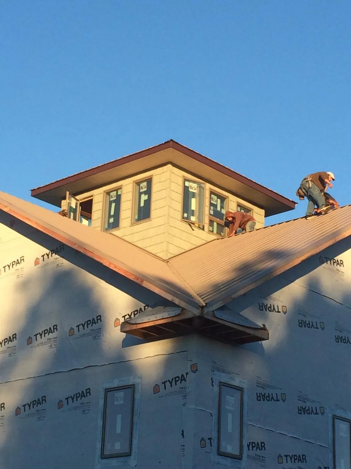Roofers working around a rooftop cupola on a new metal roof at sunset — Roof Waterproofing in Frisco by Roofing Brothers